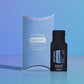 doTERRA DigestZen Digestive Blend .25 mL black sample sachet standing beside its light blue doTERRA pillow box on a glossy blue studio surface with soft reflections. doTERRA DigestZen Essential Oil Sample (.25 mL)