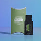 doTERRA Tea Tree .25 mL black sample sachet standing beside its green doTERRA pillow box on a glossy blue studio surface with soft reflections. doTERRA Tea Tree Essential Oil Sample (.25 mL)