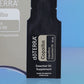 Close-up of the doTERRA Copaiba .25 mL black sample sachet standing upright in front of its taupe pillow box on a blue background. doTERRA Copaiba Essential Oil Sample (.25 mL)