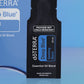 Close-up of the doTERRA Deep Blue Soothing Blend .25 mL black sample sachet standing upright in front of its blue pillow box on a blue background. doTERRA Deep Blue Essential Oil Sample (.25 mL)