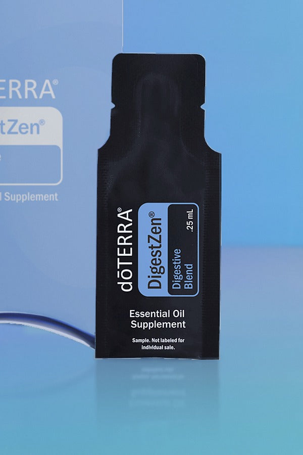Close-up of the doTERRA DigestZen Digestive Blend .25 mL black sample sachet standing upright in front of its light blue pillow box on a blue background. doTERRA DigestZen Essential Oil Sample (.25 mL)