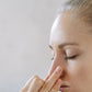 Woman with eyes closed holding her fingertips to her nose and breathing in the sweet, minty aroma of doTERRA DigestZen. doTERRA DigestZen Essential Oil Sample (.25 mL)