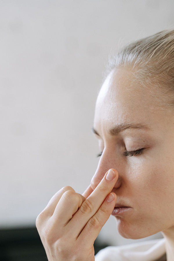 Woman with eyes closed holding her fingertips to her nose and breathing in the sweet, minty aroma of doTERRA DigestZen. doTERRA DigestZen Essential Oil Sample (.25 mL)