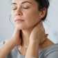 Woman massaging doTERRA Deep Blue into the back of her neck at her home office desk, eyes closed. doTERRA Deep Blue Essential Oil Sample (.25 mL)