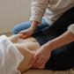 Woman relaxing on a massage mat while doTERRA DigestZen is gently massaged onto her stomach for digestive comfort. doTERRA DigestZen Essential Oil Sample (.25 mL)