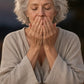 Older woman meditating at dusk, inhaling doTERRA Frankincense from her cupped hands by candlelight. doTERRA Frankincense Essential Oil Sample (.25 mL)