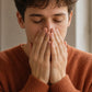 Young man in an orange sweater inhaling doTERRA On Guard from his cupped hands by an autumn window. doTERRA On Guard Essential Oil Sample (.25 mL)