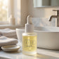 A bottle of doTERRA IKISE Booster Oil with a white dropper cap, set on a marble bathroom counter next to a sink and faucet.