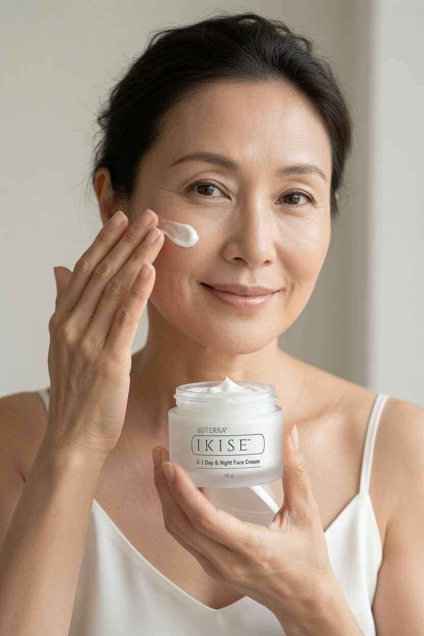 A woman applies a doTERRA IKISE Day & Night Creamto her cheek while holding a jar of KISE 2 Hour Lock Moisturizer in her other hand, set against a soft, neutral background.