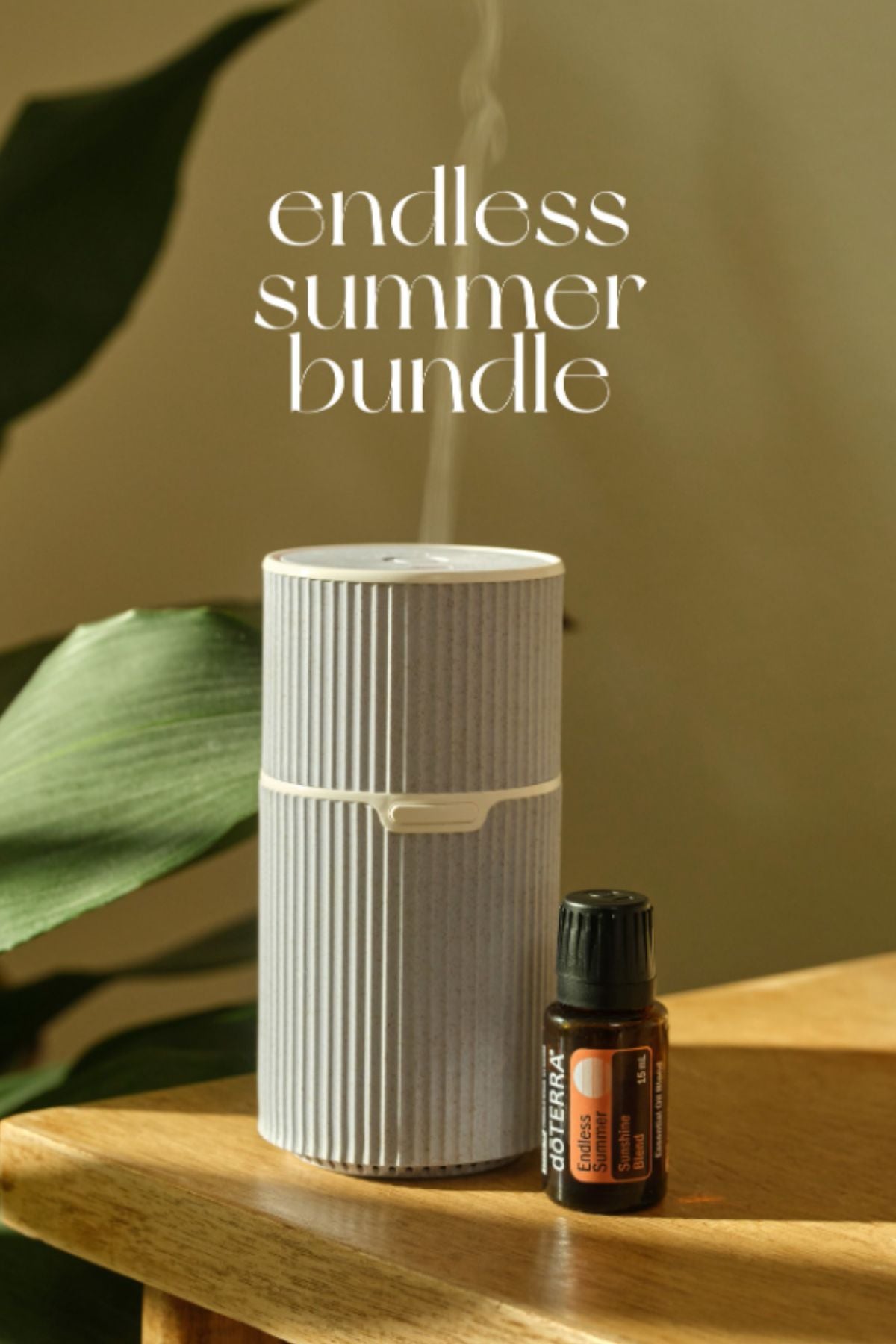 White diffuser and doTERRA essential oil bottle on a wooden surface with green leaves in the background, featuring 'endless summer bundle' text.