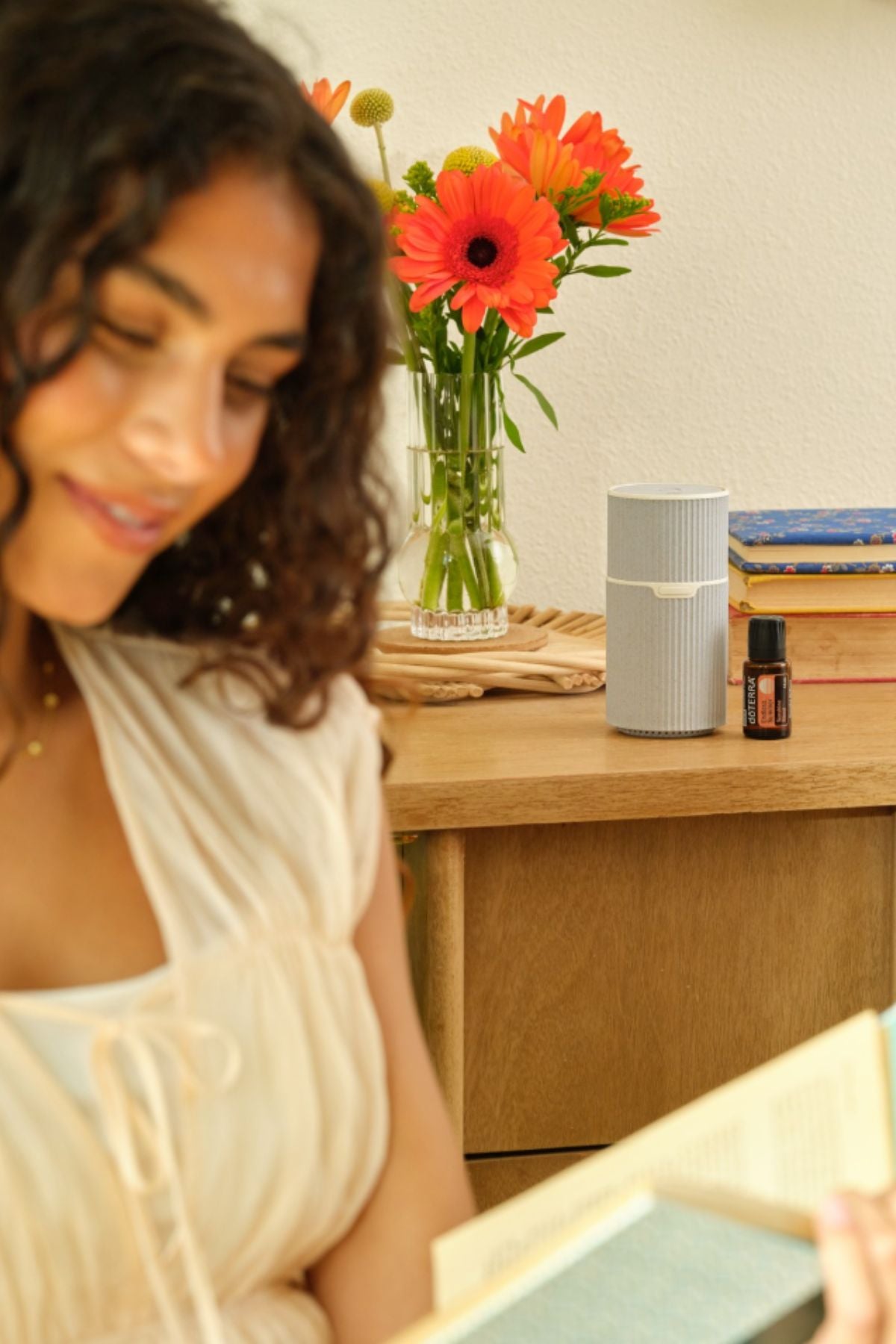 Woman sitting at a desk with a vase of flowers and a doTERRA Pilot Diffuser with Endless Summer Blend
