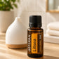 A bottle of doTERRA Litsea essential oil on a wooden table next to a white diffuser, with a blurred bathroom background.