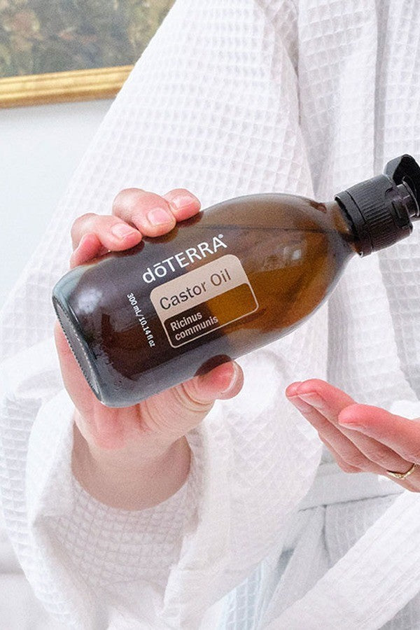 Woman pouring doTERRA Castor Oil into her hand for the Detox Bundle evening routine