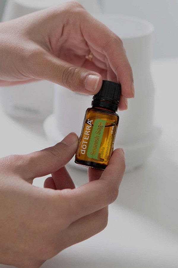Hand holding a bottle of doTERRA Spanish Sage essential oil