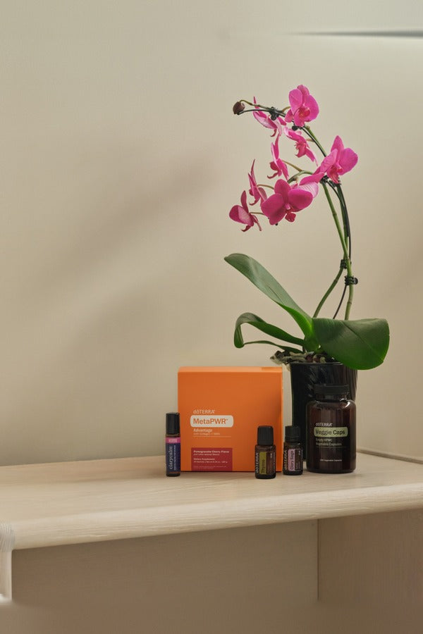 doTERRA Hormone Health Bundle on a bedroom shelf beside a pink orchid