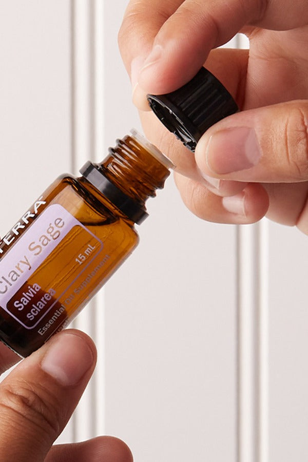 Hands opening a bottle of doTERRA Clary Sage essential oil