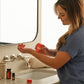 Woman applying doTERRA On Guard at her bathroom sink with the Immune Bundle
