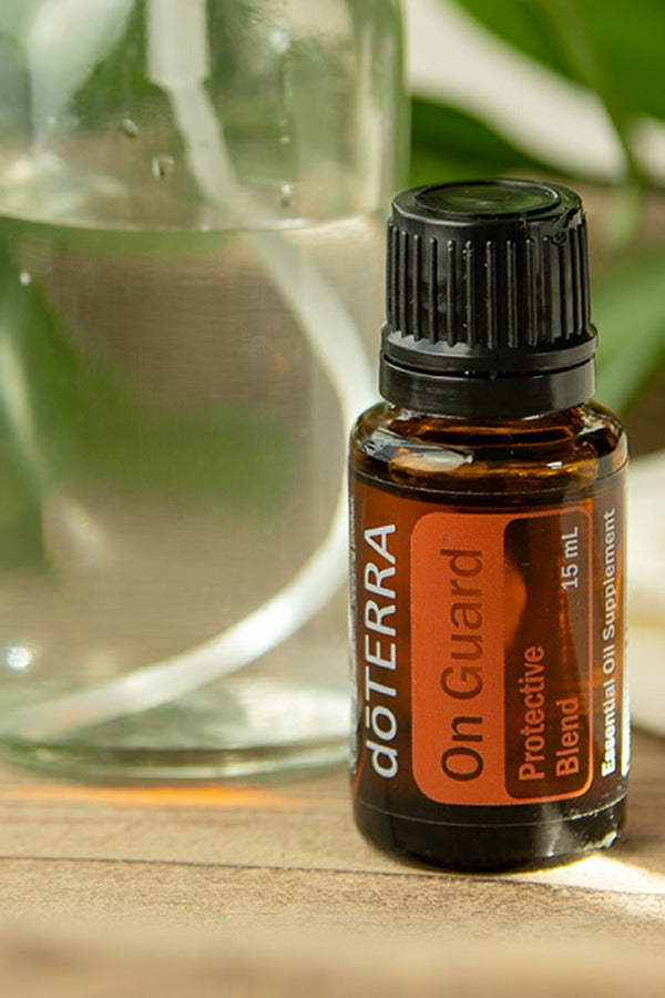 doTERRA On Guard Protective Blend bottle beside a glass of water