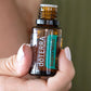 Hand holding a doTERRA SuperMint 15 mL essential oil bottle