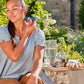 Woman applying doTERRA Deep Blue Stick to her shoulder in a sunny garden