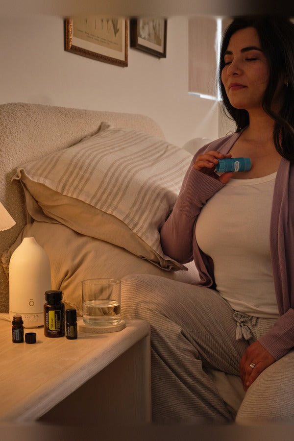 Woman relaxing on her couch with the doTERRA Respiratory Bundle in the evening