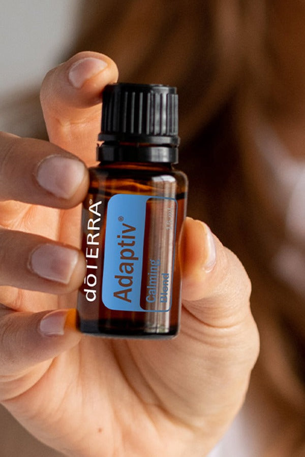 Hands holding a bottle of doTERRA Adaptiv Calming Blend