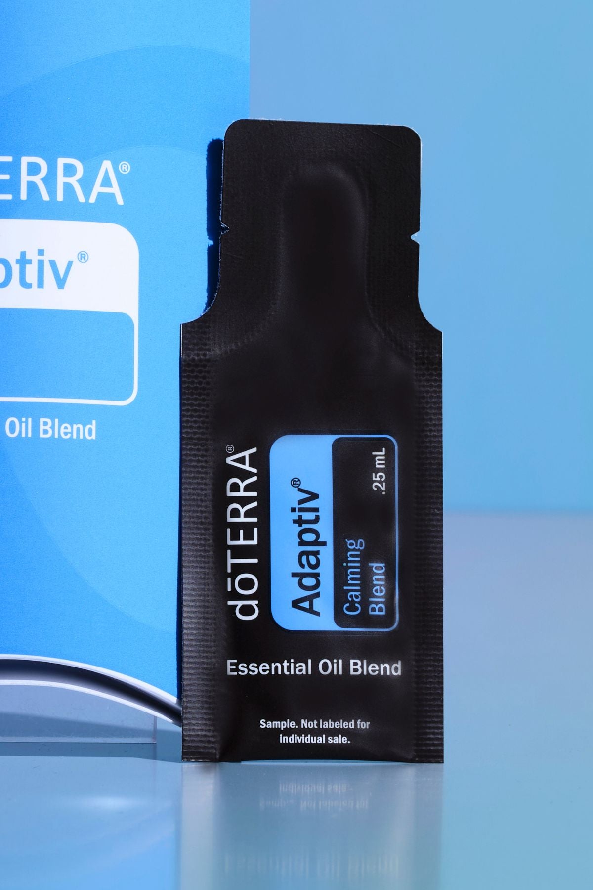A single black döTERRA Adaptiv Calming Blend essential oil blend sample sachet standing upright against a blue background. doTERRA Adaptiv Essential Oil Sample (.25 mL)