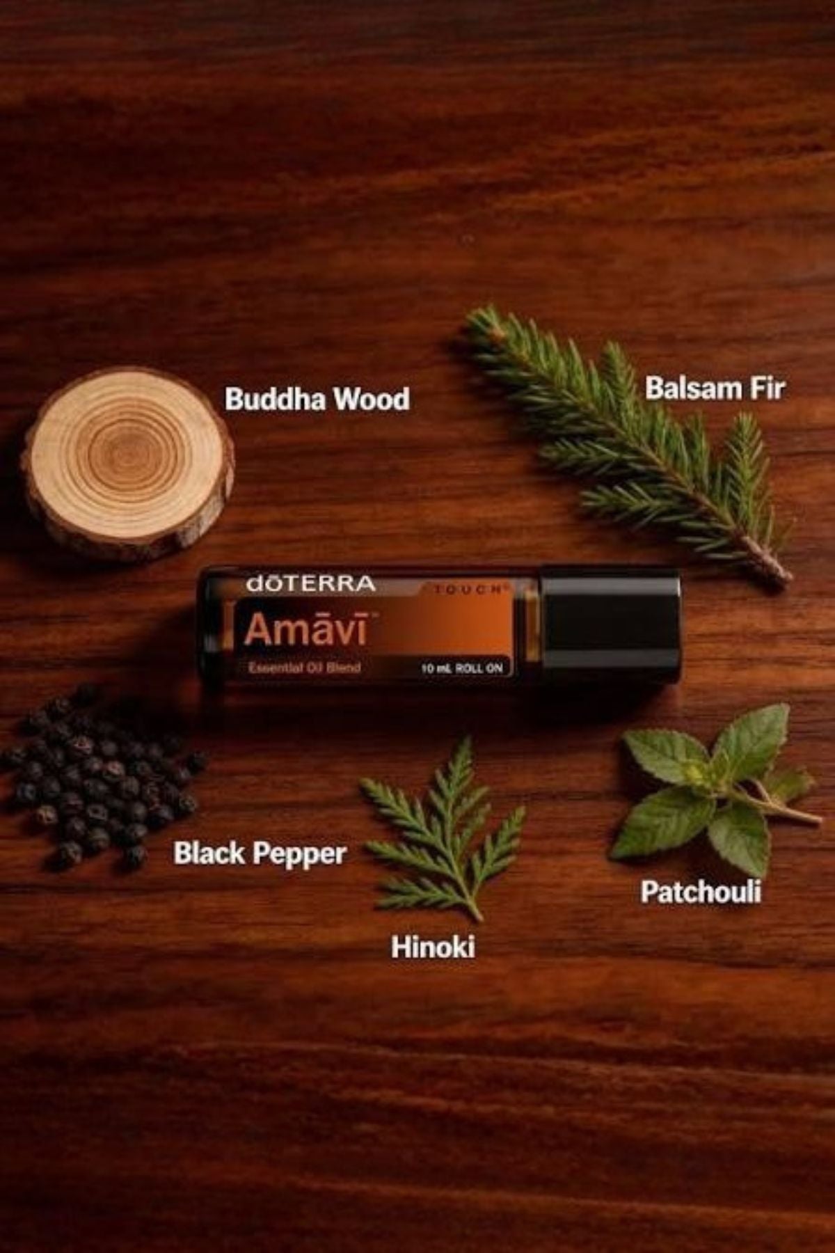 A bottle of doTERRA Amavi Essential Oil Blend is displayed on a dark wooden background, surrounded by labeled ingredients: Buddha Wood, Balsam Fir, Black Pepper, Hinoki, and Patchouli. doTERRA Amavi Touch Roll-on