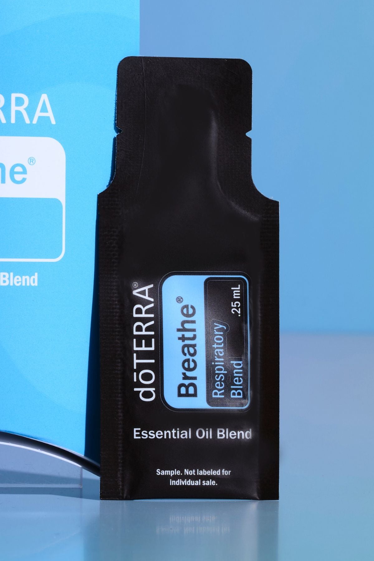 A single black döTERRA Breathe Respiratory Blend essential oil blend sample sachet standing upright against a blue gradient background. doTERRA Breathe Essential Oil Sample (.25 mL)