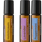 Three doTERRA Touch essential oil roll-on bottles shown side by side on a white background with a purple banner at the bottom reading BUY and GET. The bottles are amber glass with black caps, and the labels are yellow, lavender, and blue.