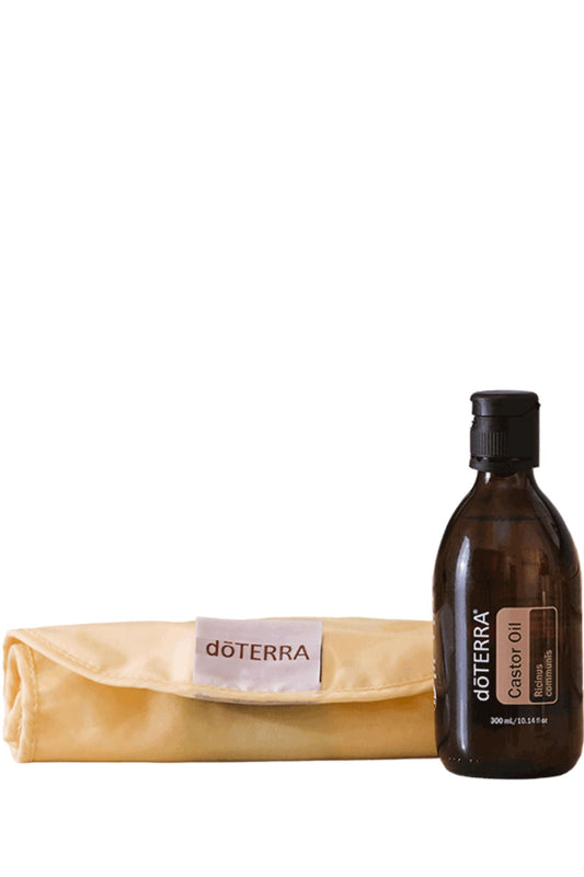 A bottle of doTERRA Castor Oil next to a folded beige doTERRA microfiber cloth on a plain white background.