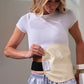 A woman wearing a white t-shirt and striped pajama pants demonstrates a beige maternity support belt with a black undergarment, showing how the support belt fits around her midsection. doTERRA CASTOR OIL pack