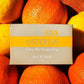 A boxed döTERRA spa bath bar labeled Citrus Bliss Invigorating, placed on top of a close-up arrangement of oranges and lemons.