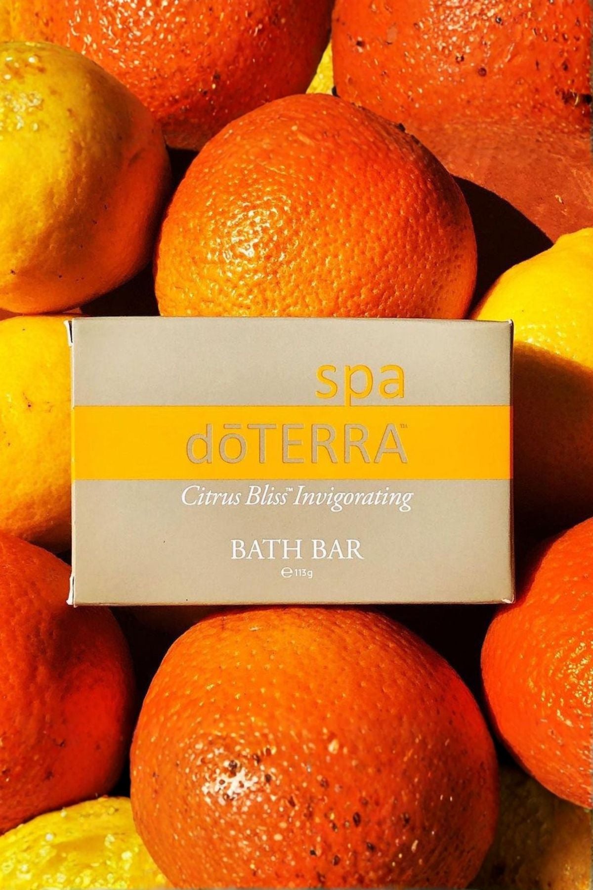 A boxed döTERRA spa bath bar labeled Citrus Bliss Invigorating, placed on top of a close-up arrangement of oranges and lemons.