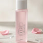 A bottle of IKISE 3 | Lotion - Smooth & Soft in a translucent light pink bottle with a white cap, styled on a light beige surface with scattered pink rose petals.